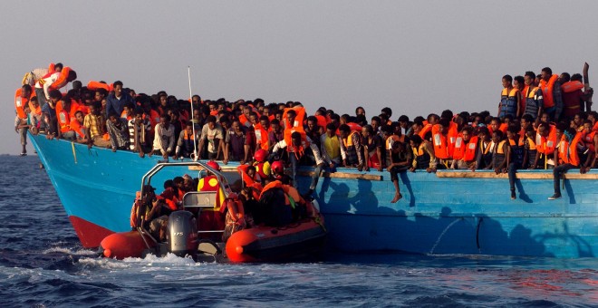 Un barco de rescate de la ONG española Proactiva se acerca a una patera de madera abarrotada de inmigrantes procedentes de Eritrea, frente a la costa de Libia en el Mar Mediterráneo. REUTERS/Giorgos Moutafis