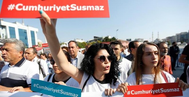 Varias presonas muestran el lema 'Cumhuriyet no se silencia' durante una concentración delante del Palacio de Justicia de Estambul (Turquía) hoy, 24 de julio de 2017. Empleados del diario se sientan en el banquillo de los acusados hoy acusados de colabora