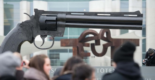 La gente mira un arma de gran tamaño colocada por activistas pacifistas frente a la Cancillería Federal en Berlín. AFP