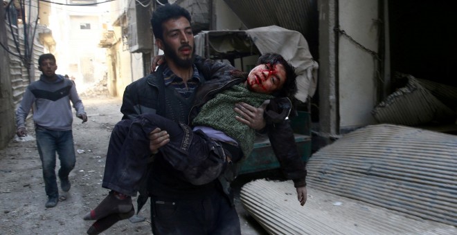 Un joven traslada a un niño herid por los bombardeos en la ciudad siria de Guta, cerca de Damasco. REUTERS/Bassam Khabieh