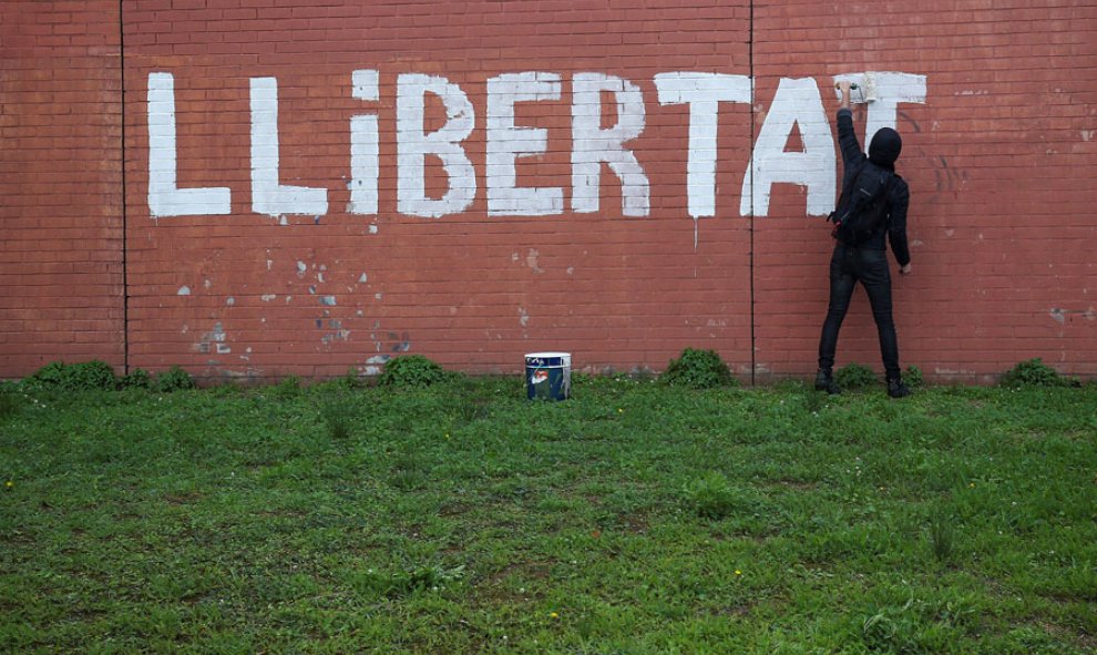 Un hombre pinta la palabra "Llibertat" en una pared de Barcelona. REUTERS/Albert Gea