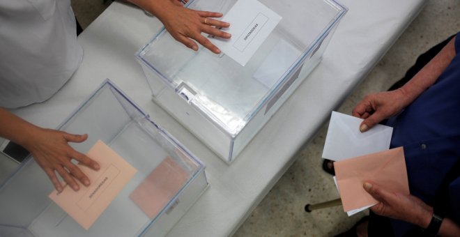 Una mujer va a depositar sus votos en las urnas correspondientes ante la Presidenta de una de las mesas electorales