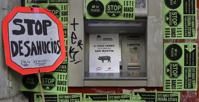 Un cajero automático en Barcelona cubierto por carteles de la plataforma antidesahucios. AFP/Lluis Gene