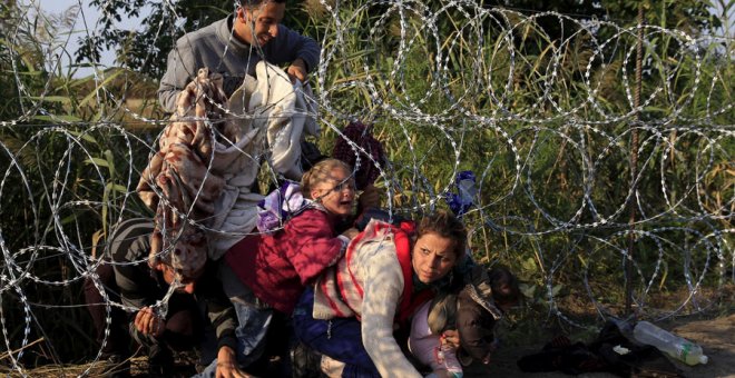 Migrantes sirios cruzan una valla para entrar en Hungría en 2015. REUTERS/Bernadett Szabo
