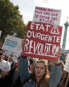 Una manifestante pone un cartel que reza 'Mamá, Macron no quiere que estudie. Revolución urgente', esta tarde, en la marcha convocada por la Francia Insumisa de Mélenchon contra la reforma laboral del Gobierno francés. REUTERS/Philippe Wojazer