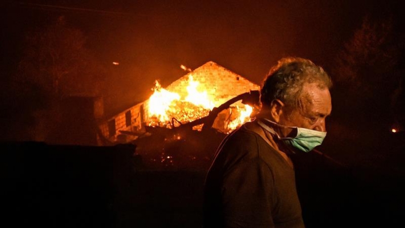 Un hombre entre las llamas en un incendio forestal declarado en Adica, Tondela (Portugal). / EFE
