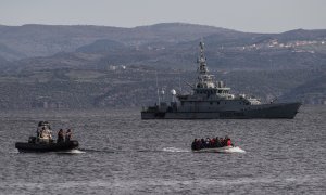 Un bote salvavidas con refugiados llega a la isla griega de Lesbos, frente a la lancha patrullera de las tropas fronterizas británicas HMC Valiant, que forma parte de la misión Frontex.